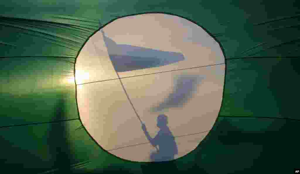 A supporter is silhouetted against a giant flag of Malaysia&#39;s opposition Pan-Malaysian Islamic Party as he waves the party&#39;s flag ahead of the upcoming general elections in Pekan, Pahang state. 