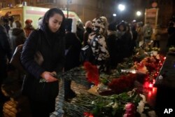 A woman lays flowers at the well-known military choir's building in Moscow, Dec. 25, 2016.