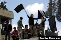 FILE - Protesters carry Nusra Front flags and shout slogans during an anti-government protest after Friday prayers in the town of Maarat al-Numan in Idlib province, Syria, March 11, 2016.
