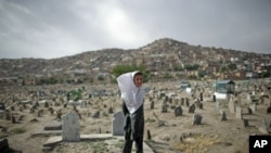 A girl, who sells water, closes her eyes as the wind blows her scarf at a cemetery in Kabul, Afghanistan, June 5, 2011