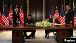 Дональд Трамп и Ким Чен Ын подписывают документы, подтверждающие ход переговоров. Сингапур, 12 июня 2018