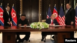 U.S. President Donald Trump and North Korea's leader Kim Jong Un sign documents that acknowledge the progress of the talks and pledge to keep momentum going, after their summit at the Capella Hotel on Sentosa island in Singapore, June 12, 2018. 