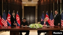U.S. President Donald Trump and North Korea's leader Kim Jong Un sign documents that acknowledge the progress of the talks and pledge to keep momentum going, after their summit at the Capella Hotel on Sentosa island in Singapore, June 12, 2018. 