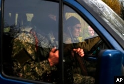 一名欧安会观察员（右一，背景处）在乌克兰东部的斯拉维扬斯克工作，前景为武装亲俄分子驾驶的汽车从镜头前开过 。摄于2014年4月24日。