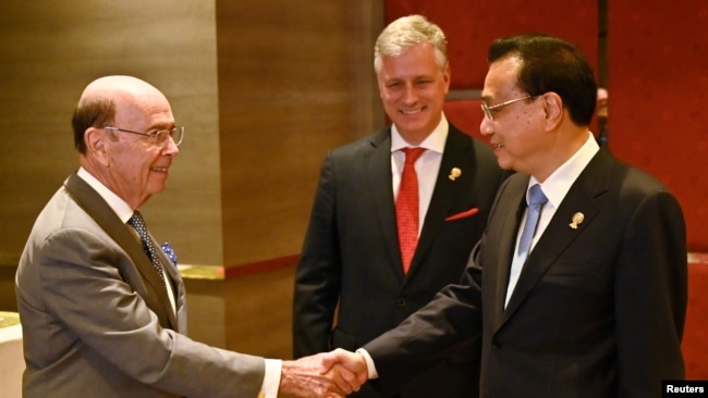美国商务部长罗斯（左）与中国总理李克强在东盟峰会上握手，美国国家安全顾问罗伯特·奥布莱恩站立在两人身旁。（2019年11月4日）