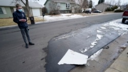 A man looks over debris that fell off a plane as it shed parts over a neighborhood in Broomfield, Colo., Saturday, Feb. 20, 2021. (AP Photo/David Zalubowski)
