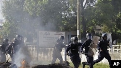 Liberian police advance past burning barricade as they chase opposition party supporters in Monrovia, Nov. 7, 2011.