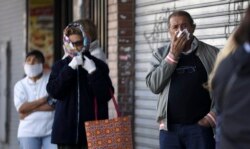 La gente, usando diferentes métodos para taparse la boca y la nariz, hacen cola frente a un banco en Buenos Aires, Argentina, el 4 de abril de 2020.