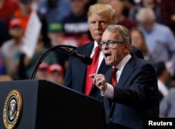 U.S. President Donald Trump listens as Ohio gubernatorial nominee and Ohio Attorney General Mike Dewine speaks during a campaign rally in Cleveland, Ohio, Nov. 5, 2018.