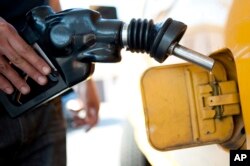 FILE - A customer pumps gas into his dual-tank pickup truck at a 76 gas station in Los Angeles, Aug. 10, 2012.