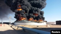 Dalam foto yang dirilis oleh National Oil Corporation, asap dan api membubung dari tangki penyimpanan minyak yang dibakar di terminal Ras Lanuf, ditengah pertempuran antara para faksi yang bertikai di Libya, 18 Juni 2018.