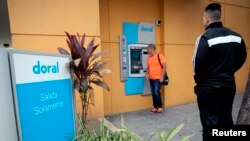 FILE - A man looks at the screen of an ATM of the failed Doral Bank in San Juan, Puerto Rico, February 27, 2015.