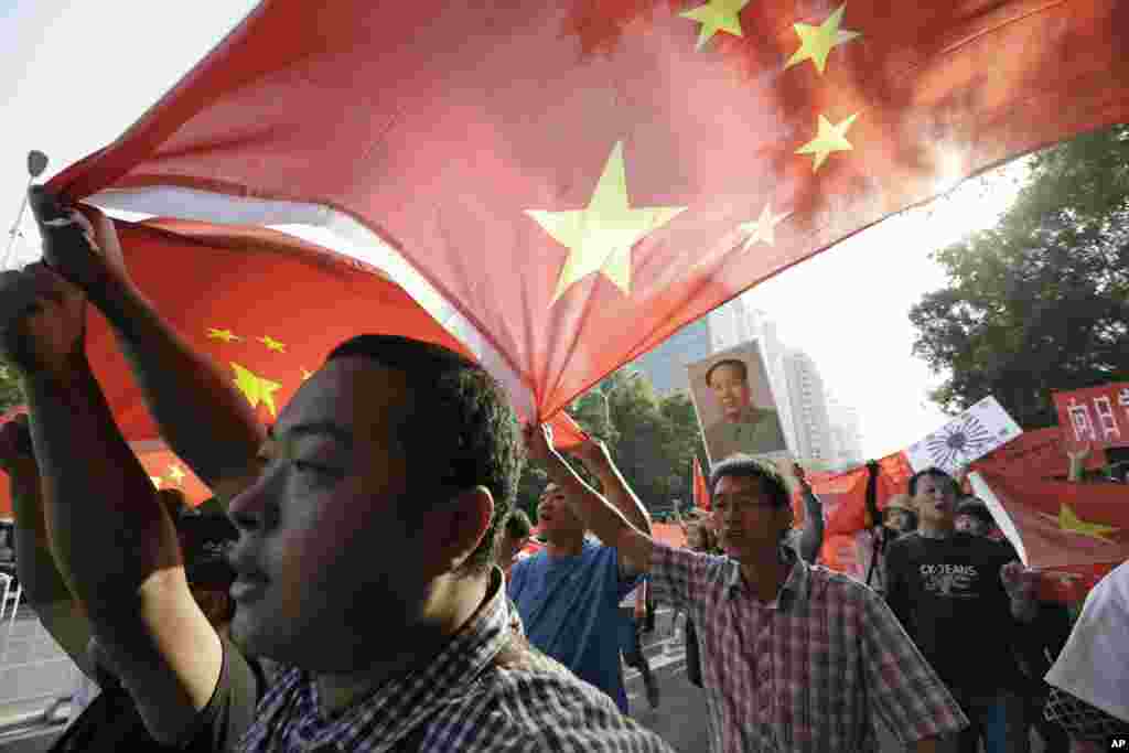 Chinese protesters march with a national flag and a portrait of former Chinese leader Mao Zedong near the Japanese Embassy in Beijing, China, September 16, 2012. 