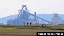 FILE - People play golf near the Tata Steel plant in Hartlepool in north east England on May 3, 2021.