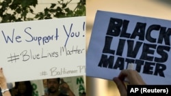 From left, a Baltimore police supporter holds a "Blue Lives Matter" poster, May 30, 2015; and a man holds a sign saying "Black Lives Matter" during a protest of shootings by police by the White House in Washington, July 8, 2016.