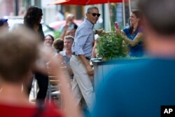 FILE - People take photographs as President Barack Obama, center, and first lady Michelle Obama walk into the Oyamel Cocina Mexicana restaurant in Washington for dinner, May 28, 2016.