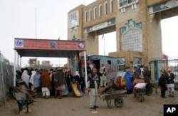 FILE - Families wait to cross the Afghanistan-Pakistan border point, in Spin Boldak, Kandahar province, Afghanistan, March 7, 2017.