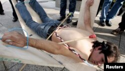 FILE - A Syrian opposition member of government shows what they say is one of the torture methods used in Syrian prisons during a demonstration in Beirut calling for more human rights in Syria, Dec. 10, 2009. 