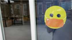 A sign on a door into a food hall just north of downtown Charlotte, NC, tells guests to wear a mask. (Salim Fayeq/VOA)