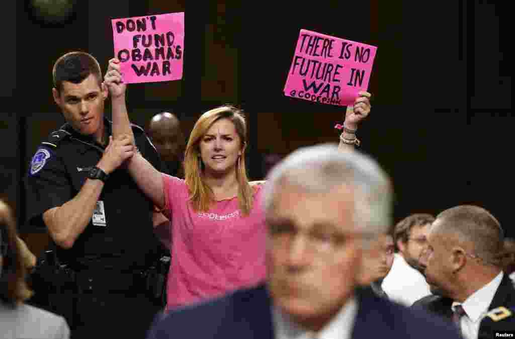 An anti-war protester is escorted out of the Senate Armed Services Committee hearing by a police officer in Washington, Sept. 16, 2014