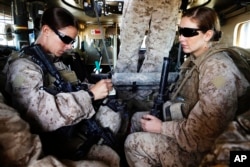 FILE - Marinir AS dan Pemimpin Tim Perempuan Sersan Sheena Adams (kiri) dan H.N. Shannon Crowley dari Batalyon 1, 8 Marinir AS duduk di dalam kendaraan lapis baja sebelum meninggalkan pangkalan militer di Musa Qala, Afghanistan selatan di provinsi Helmand.