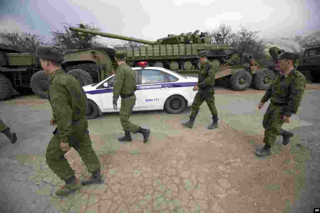 Xe cảnh sát và binh lính Nga&nbsp;đi phía sau xe tăng của Ukraine tại Perevalnoe, bên ngoài Simferopol, Crimea, ngày 26/3/2014.
