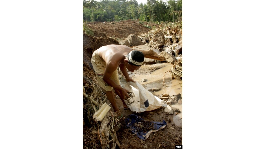 Marsudi, korban bencana tanah longsor Purworejo, mengumpulkan besi bekas dari reruntuhan rumahnya yang hancur (Foto: VOA/Nurhadi)