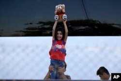 A migrant child holds up her doll during a police operation to evacuate an unused terminal building of the old international airport, which is used as a shelter for about 600 refugees and migrants, in Athens, June 2, 2017.