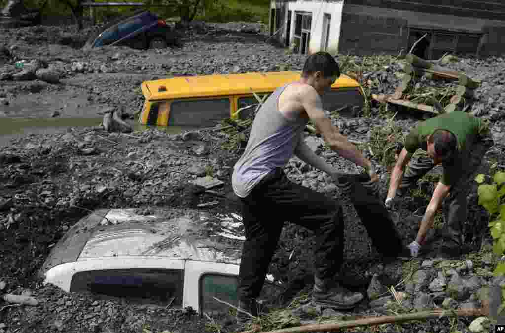 Residents try to excavate a car trapped in the mud caused by a landslide at the village of Topcic Polje, near the Bosnian town of Zenica, 90 kilometers north of Sarajevo, Bosnia-Herzegovina.