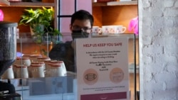 FILE - A sign explaining the LA County Mandate is posted for customers inside the Intelligentsia Coffee in Los Angeles, Nov. 29, 2021.