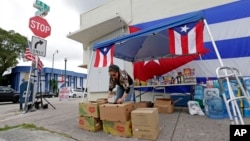 Volunteer Teresa Cruz places donated food items in a box for hurricane relief bound for Puerto Rico, Sept. 27, 2017, in the Little Havana area in Miami. 