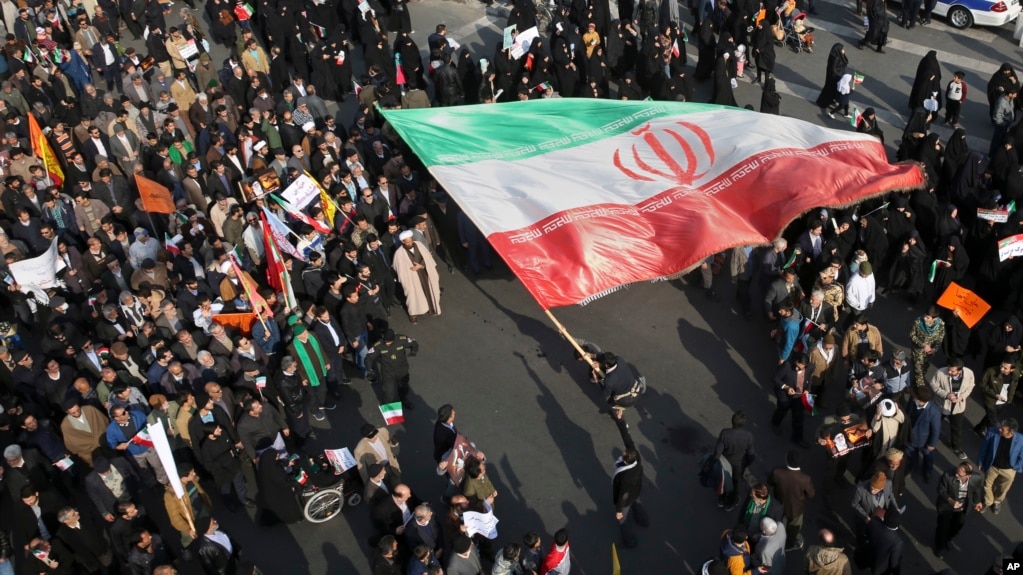 En esta foto proporcionada por la agencia de noticias Tasnim, un manifestante ondea una enorme bandera iraní durante las protestas en Mashad, Iran, el jueves 4 de enero.