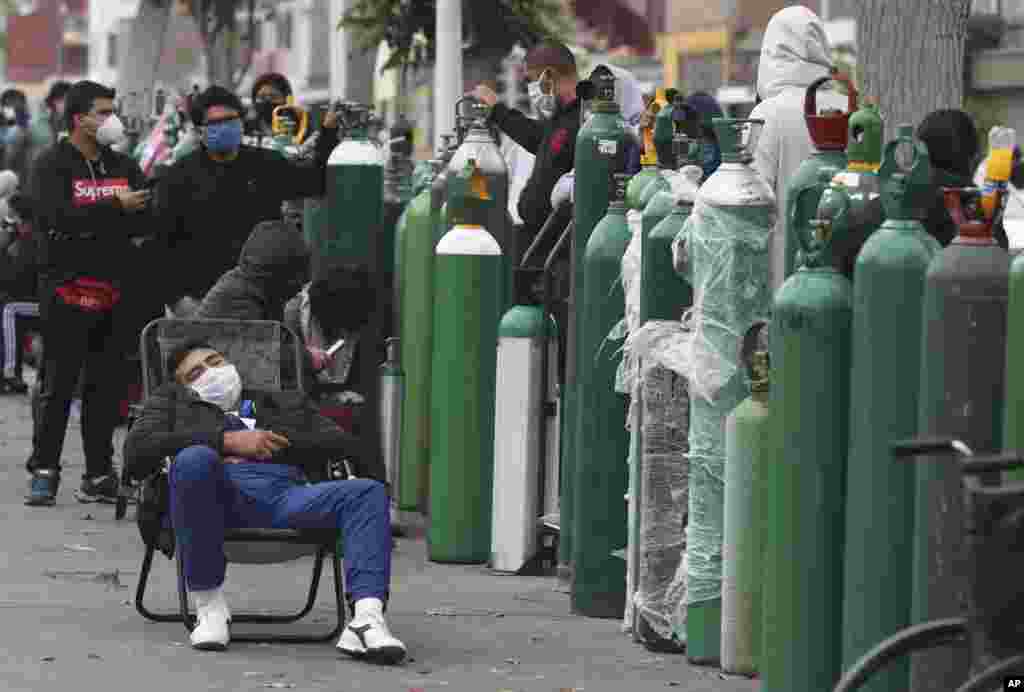 People wearing masks amid the spread of the new coronavirus wait for hours, some for 10 hours, to refill their oxygen cylinders at a shop in Callao, Peru, June 8, 2020.