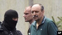 Serbian police officers escort Goran Hadzic (R), after he visited his terminally ill mother in Novi Sad July 22, 2011. Serbia on Friday extradited Goran Hadzic, the last ethnic Serb wanted by the International Criminal Court in The Hague, in a symbolic mo
