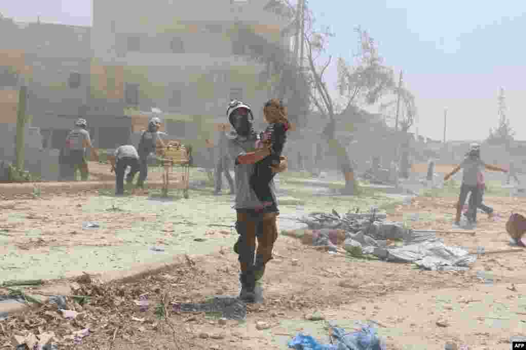 A Syrian rescue woker carries a child in the Maadi district of eastern Aleppo after regime aircrafts reportedly dropped explosive-packed barrel bombs, Aug. 27, 2016.