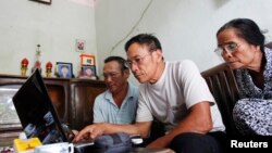FILE - Veteran Le Dung (C) reads articles on the Internet with Dang Van Dat (L) and Tran Thi Thanh Kiem (R) at his house in Van Giang district, outside Hanoi, Vietnam.
