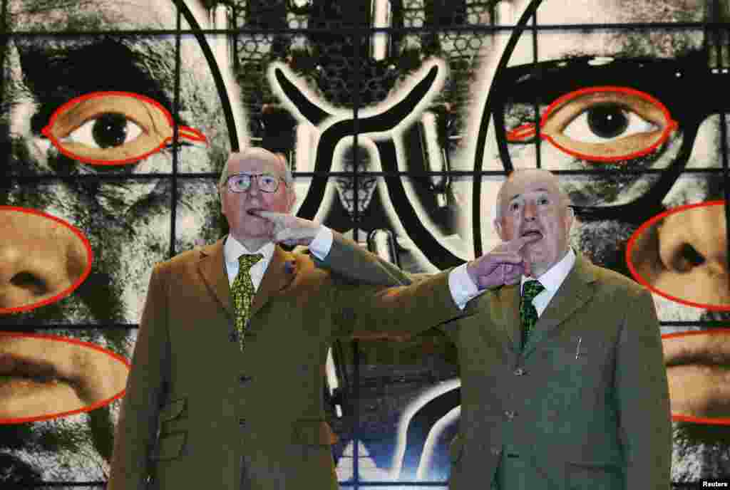 Italian artist Gilbert Proesch (R) and British artist George Passmore, known as Gilbert &amp; George, pose with their artwork &quot;Scapegoating&quot; during the launch of their new exhibition &quot;Scapegoating&quot; at the White Cube gallery in Bermondsey, London.