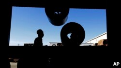 FILE - Workers load rolls of sheet metal at LMS International in Laredo, Texas, Nov. 21, 2016. Donald Trump’s campaign promise to abandon the North American Free Trade Agreement helped win over Rust Belt voters who felt left behind by globalization. But U.S. border cities that have thrived under the trade pact now worry that an economic reckoning could be coming its way.