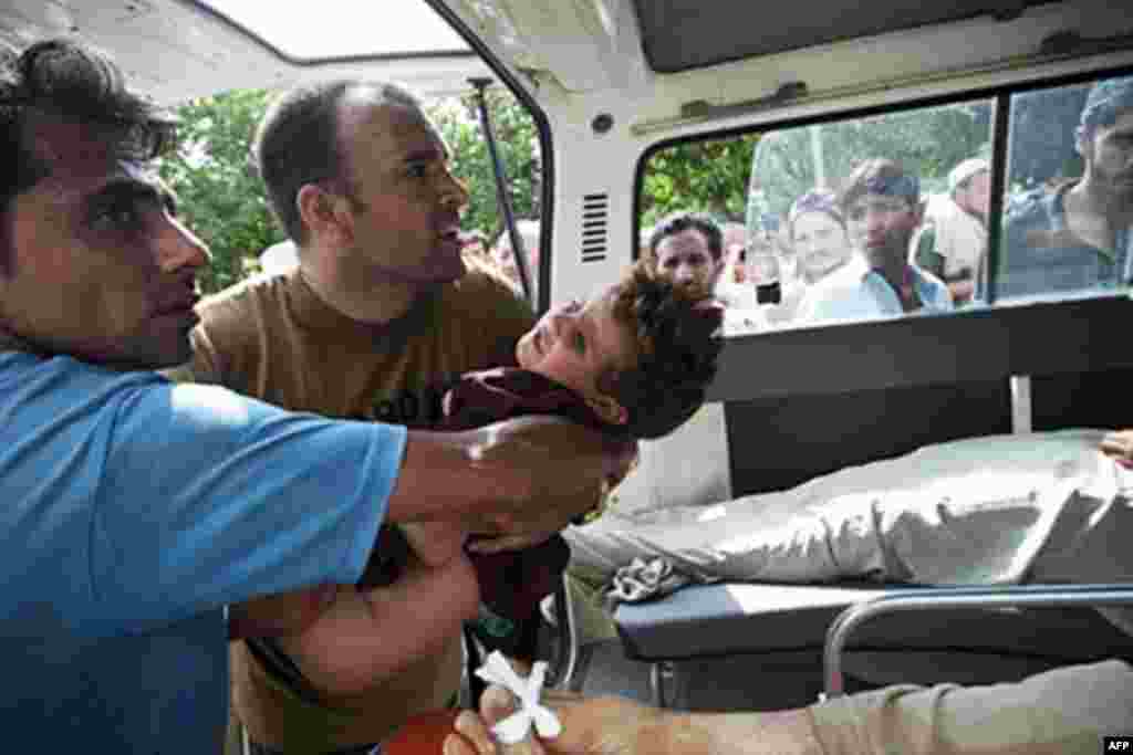 Pakistani aid volunteers life a boy into an ambulance transporting him to a hospital after initial medical attention at a field hospital set up inside a college on the outskirts of Nowshera on August 2, 2010. Fears were growing Monday for up to 2.5 millio