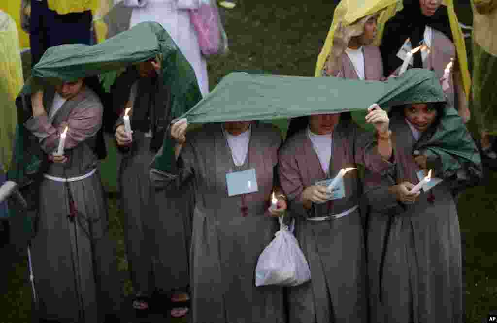 Para biarawati Filipina memegang lilin di bawah curahan hujan sementara Paus Fransiskus melaksanakan misa terakhirnya di Manila, 18 Januari 2015.