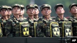 FILE - North Korean soldiers, carrying packs marked with a nuclear symbol, take part in a parade in Pyongyang, North Korea, July 27, 2013. North Korea warned Friday it could revive a state policy aimed at strengthening its nuclear arsenal if the United States does not lift economic sanctions against the country.