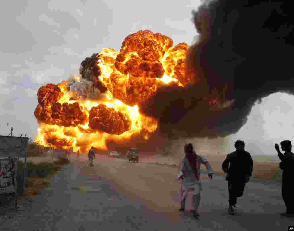 Men run away from burning oil tankers, used to carry fuel for NATO forces in Afghanistan, as they explode after they were attacked on the outskirts of Quetta August 19, 2011. Five NATO trucks have been set on fire in Mastung in the province of Baluchistan
