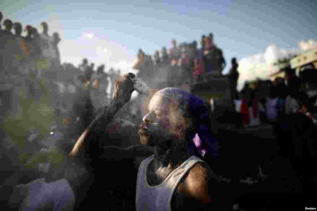 A man covers his face with baby powder during Voodoo celebrations in a burial place in Port-au-Prince, Haiti, November 1, 2018.