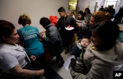 Darly Sotto, 21, of Guatemala holds her son, 1-year-old Jorge Sotto, as people check into the Catholic Charities shelter in McAllen, Texas, Jan. 11, 2019.