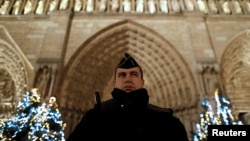 A French gendarme stands guard as heavy police forces secure the access to Notre-Dame cathedral during Christmas celebrations in Paris, France, Dec. 24, 2016. 