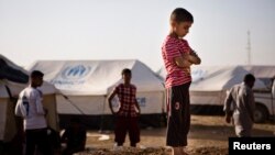 A boy, who fled from the violence in Mosul, stands near tents in a camp for internally displaced people on the outskirts of Erbil in Iraq's Kurdistan region, June 14, 2014. 