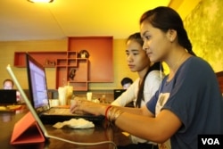 FILE - University students from the Royal University of Phnom Penh check the Internet in a coffee shop along the city's Russian Federation Boulevard, June 13, 2014.