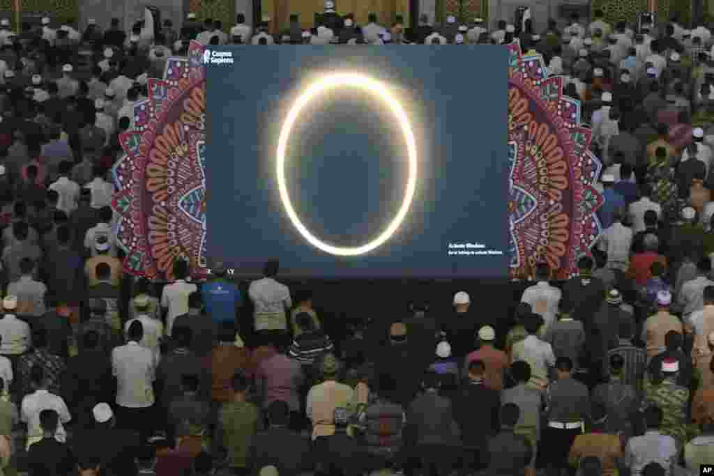 Muslim men perform a special &#39;kusoof&#39; prayer as a live report of the annular solar eclipse is broadcast on a large screen at a mosque in Surabaya, East Java, Indonesia.