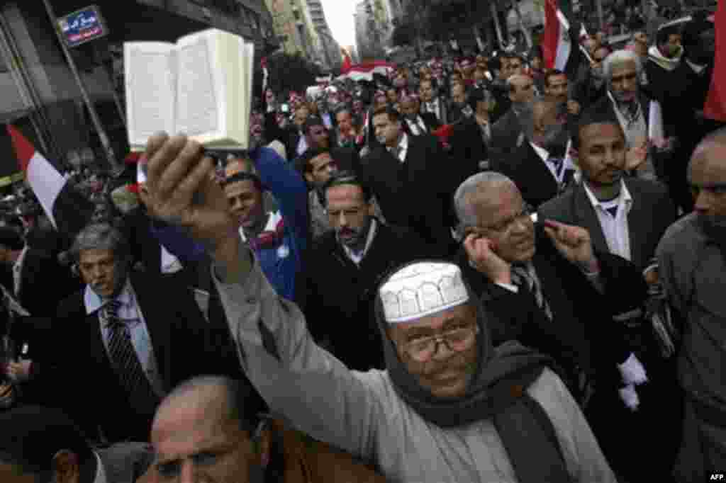 An elderly Egyptian raises a copy of Islam's holy book, the Quran, as he marches with lawyers in black robes in Cairo, Egypt, Thursday, Feb. 10, 2011. Labor unrest across the country gave powerful momentum to Egypt's wave of anti-government protests. With