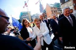 FILE - German President Joachim Gauck (R) and Chancellor Angela Merkel (C) meet wellwishers in the streets of Frankfurt, Germany, Oct. 3, 2015. Germany's political leaders celebrated the country's 25th anniversary since the reunification of East and West Germany.